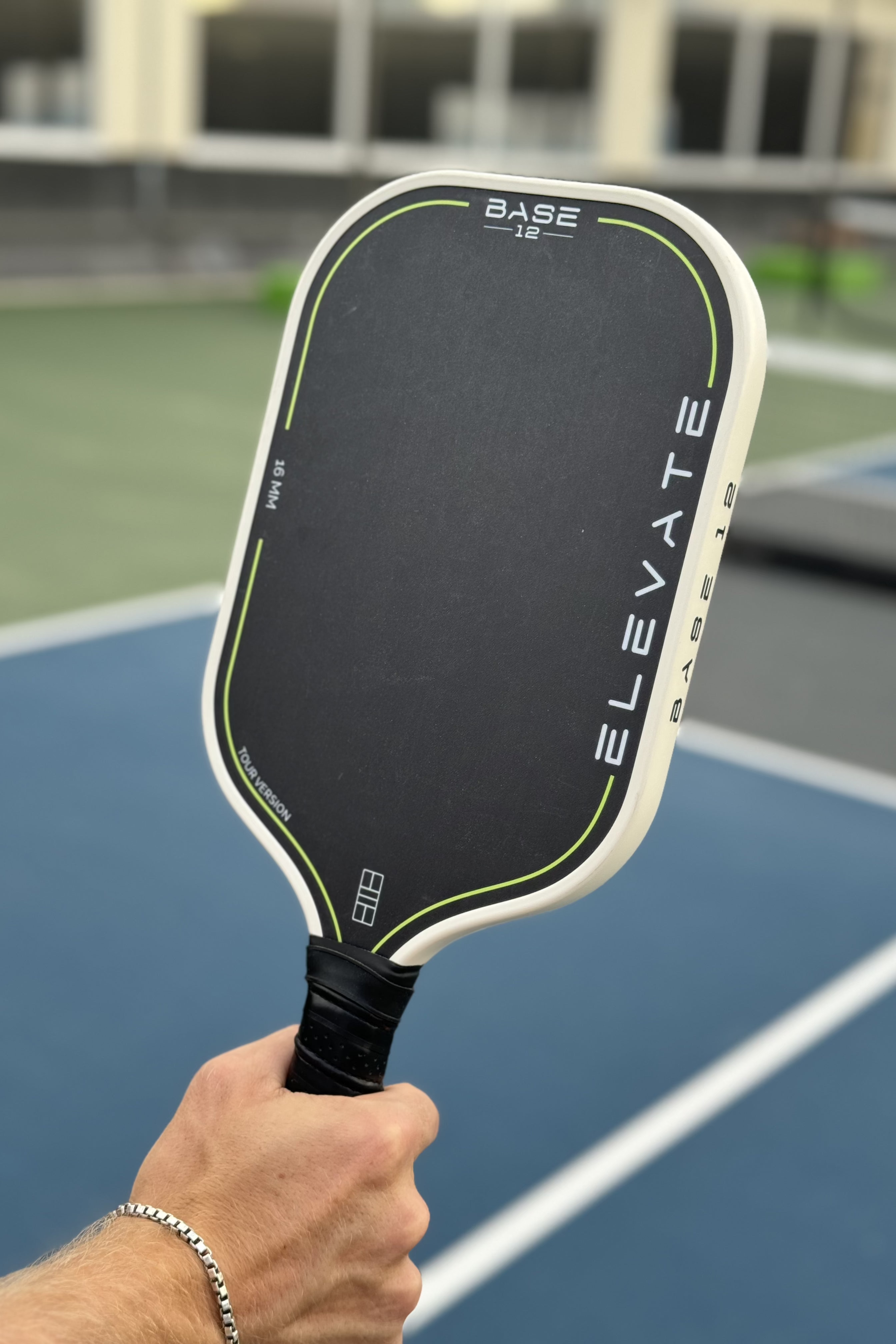 Pickleball-Schläger ELEVATE von BASE12 wird auf dem Spielfeld in der Hand gehalten